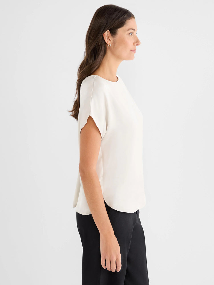 Off-white woven tee with a round neck, short sleeves, relaxed fit, and a curved hem.