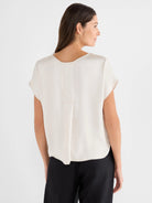 Light cream gloss woven tee with a relaxed fit, short sleeves, curved back neckline, and vertical back seam.