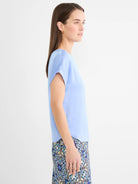 Pale blue smooth woven tee with loose cap sleeves and a curved hem.