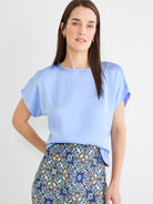 Periwinkle woven tee with a glossy sheen, boat neck, and short, draped sleeves.
