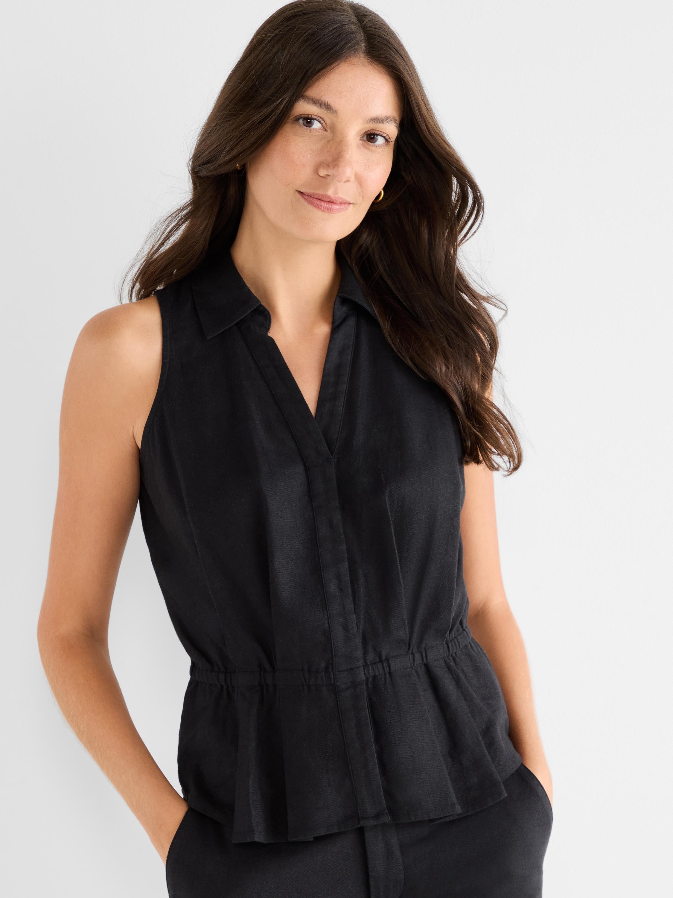 Black sleeveless jumpsuit featuring a sharp collar, V-neck placket, and a gathered elastic waist detail.