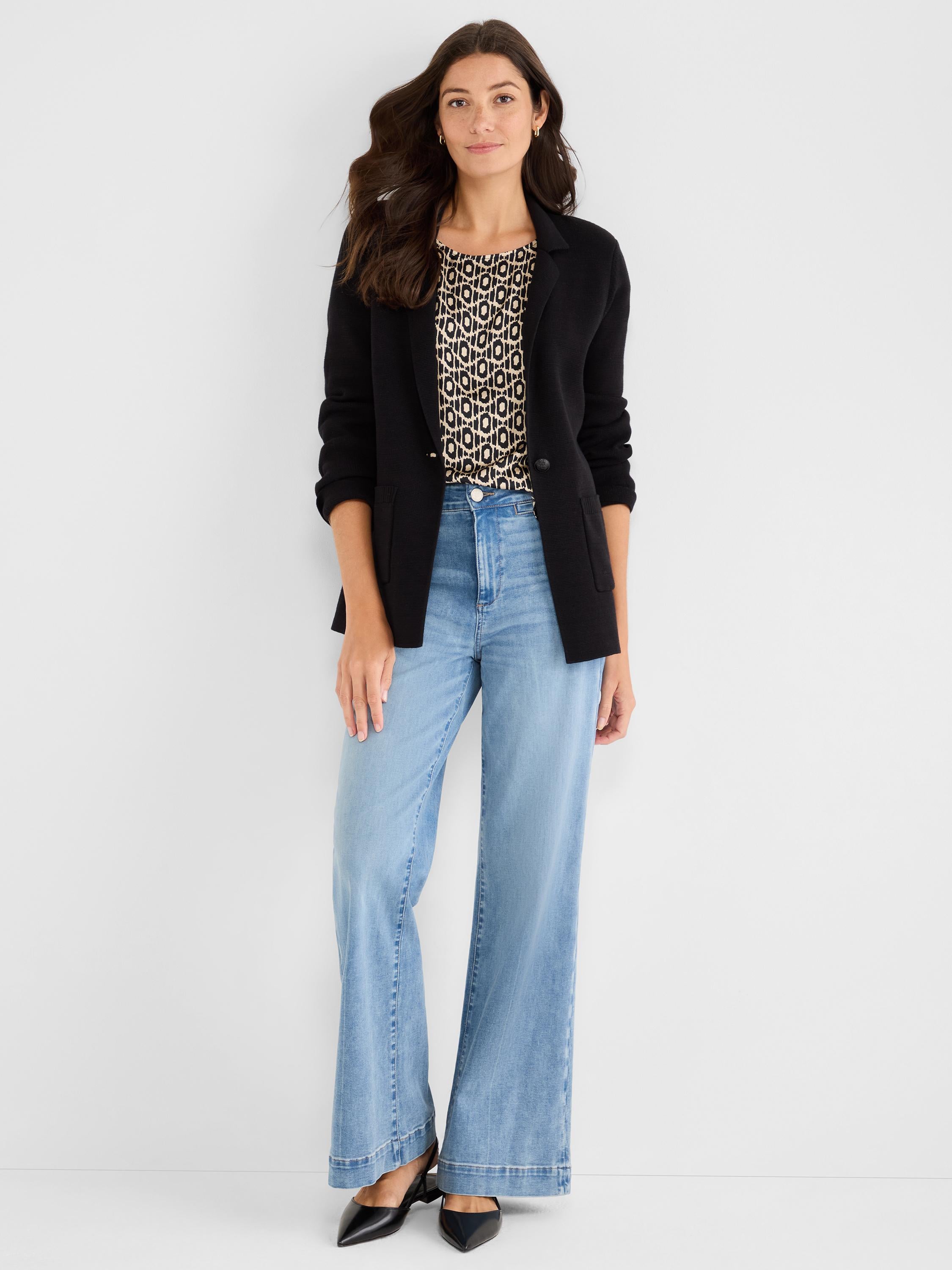 Black knit blazer and geometric print blouse styled with high-waist, light wash, full-length wide-leg jeans.