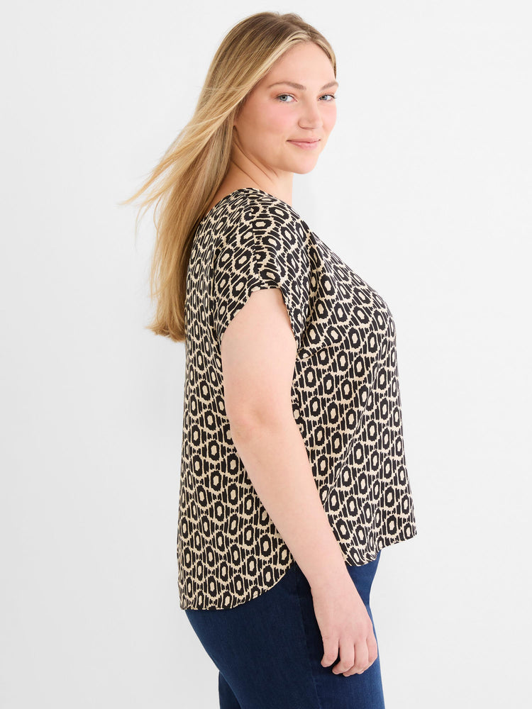 Black and beige patterned short-sleeve top featuring a loose fit and a scoop neck, paired with dark wash jeans.