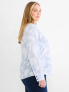 Sky blue and white striped top with white jacquard floral patterns. Long sleeves and dark buttoned cuffs.