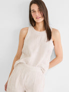 Cream gauze tank top with thin tan pinstripes, round neck, and sleeveless.