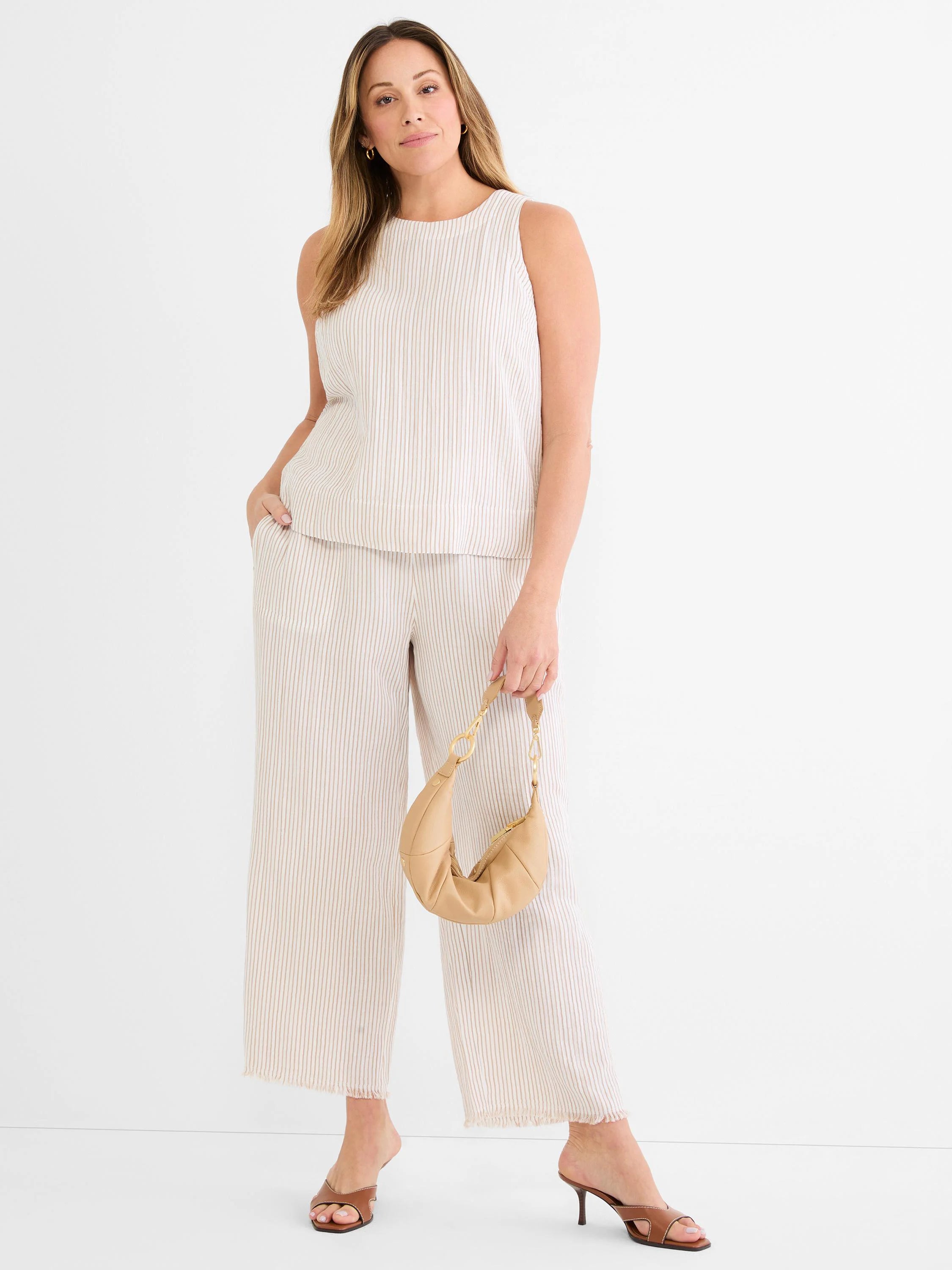 Cream gauze tank with thin tan vertical pinstripes. Sleeveless, high rounded neck. Model wears matching striped pants.