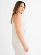 White sleeveless tank top with thin tan vertical pinstripes.