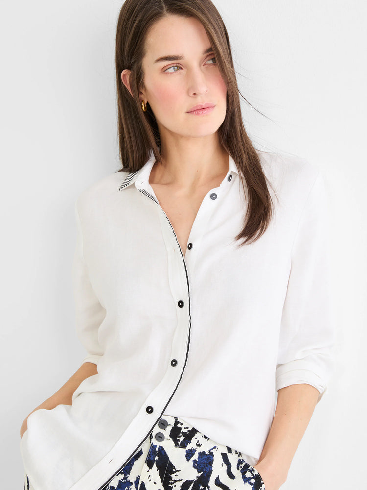 White linen shirt with black striped trim on collar & front button closure. Features black buttons.