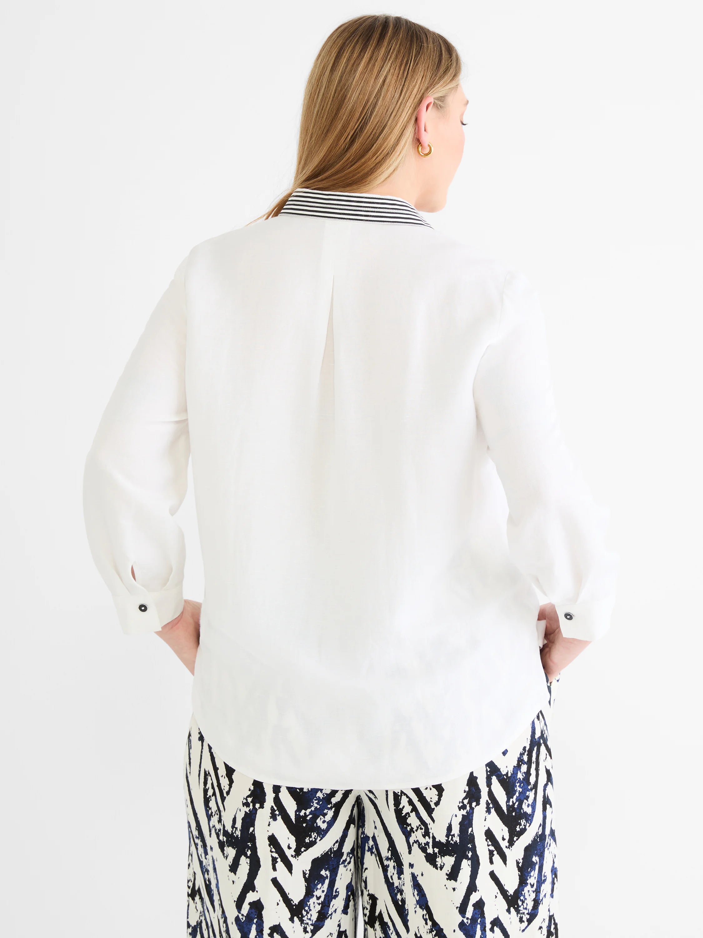 White linen shirt with black and white striped collar. Dark buttons on the cuffs.