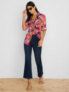 Vibrant crinkle shirt in red, pink, orange, & teal abstract floral pattern. Features a collar & rolled short sleeves.