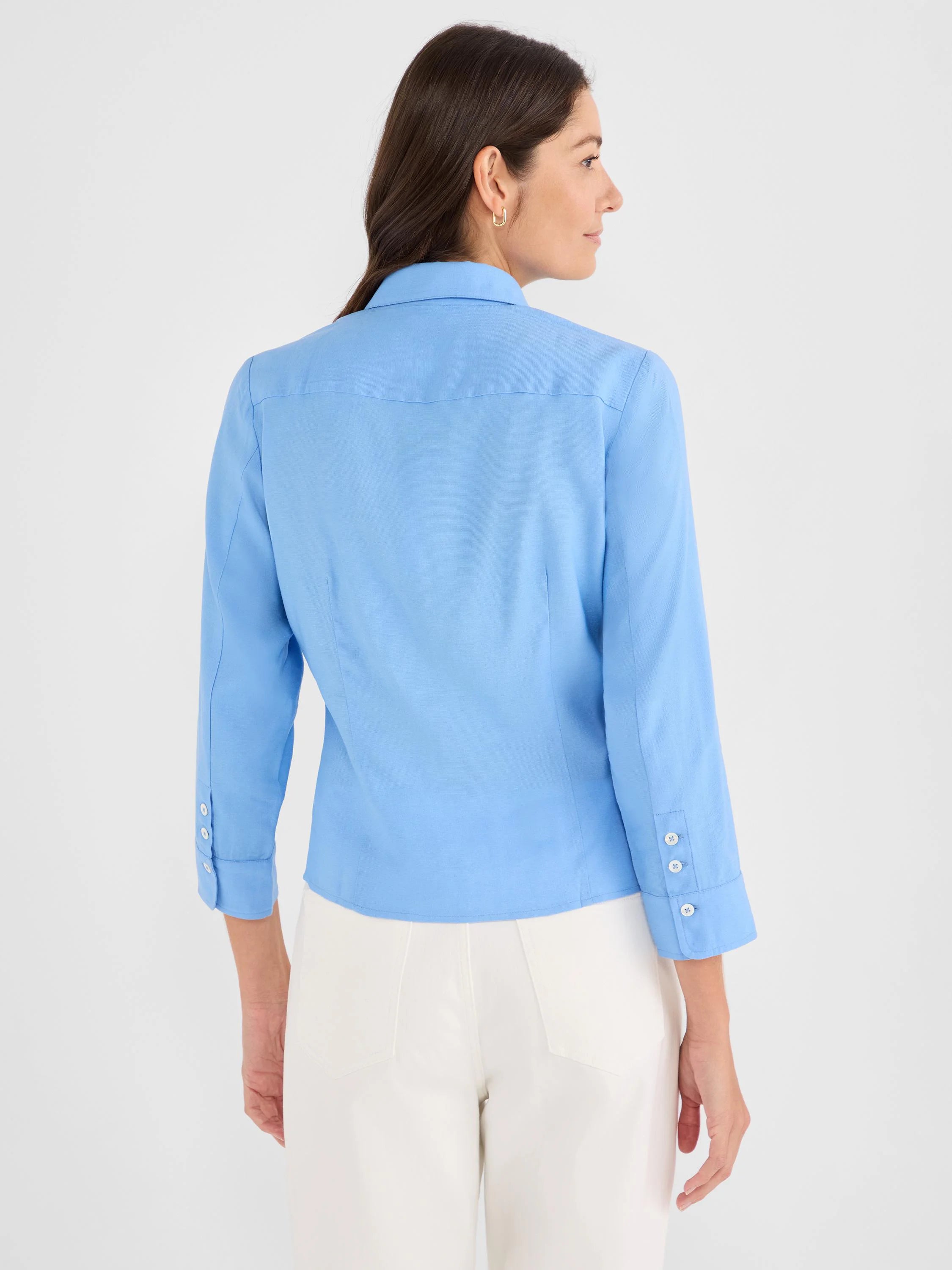 Back of a light blue 3/4-sleeve shirt with white buttons on the cuffs.