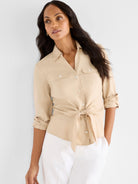 Tan collared tie-front shirt with subtle dot texture, button front, two chest pockets, and rolled sleeves.