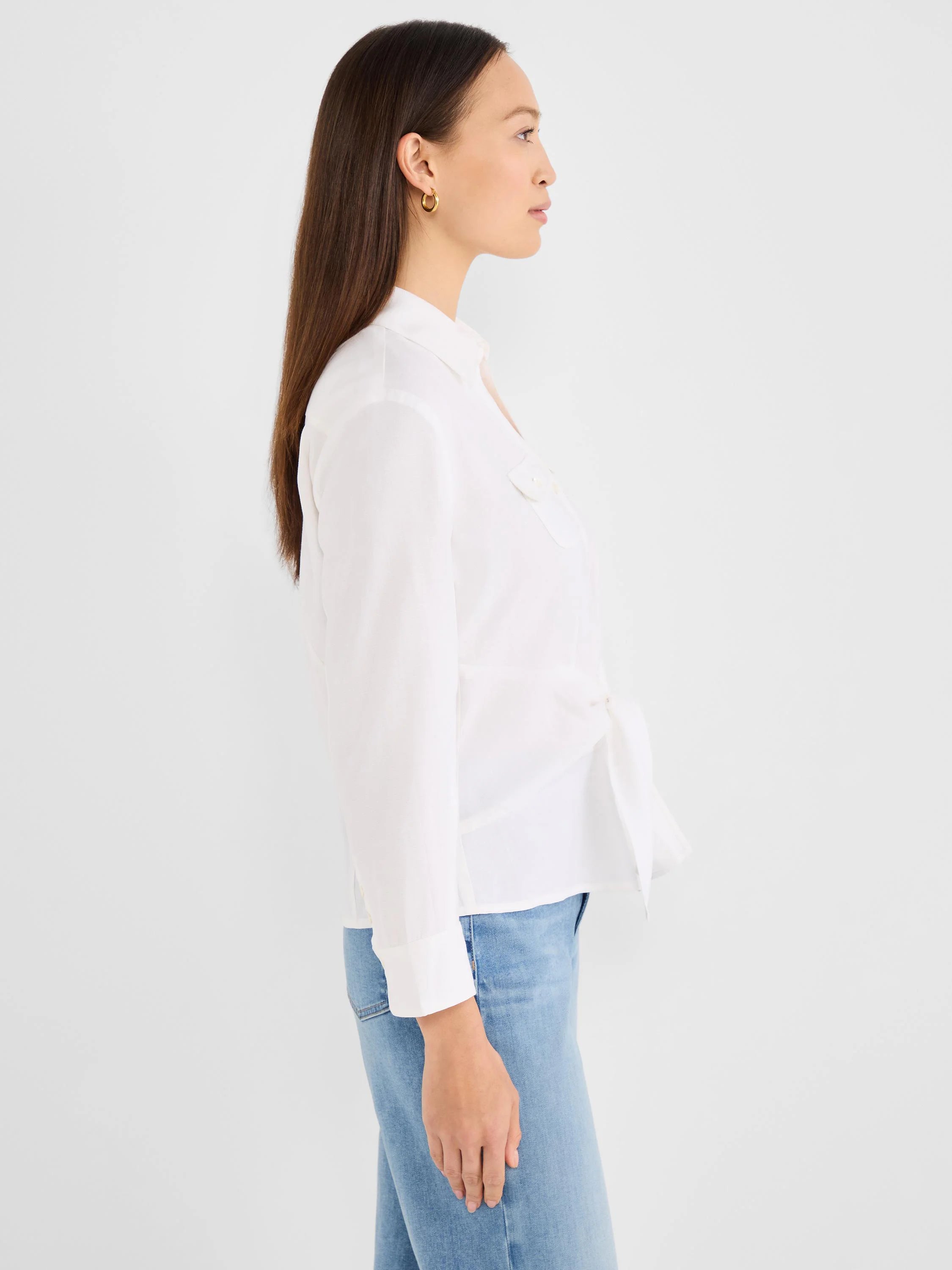 White collared tie-front shirt with long sleeves and a chest pocket, styled with light blue jeans.