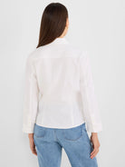 White collared shirt with back yoke, long sleeves, and buttoned cuffs, viewed from behind.