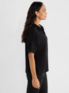 This relaxed fit black short-sleeve blouse features an open collar and stylish cuffed sleeves.