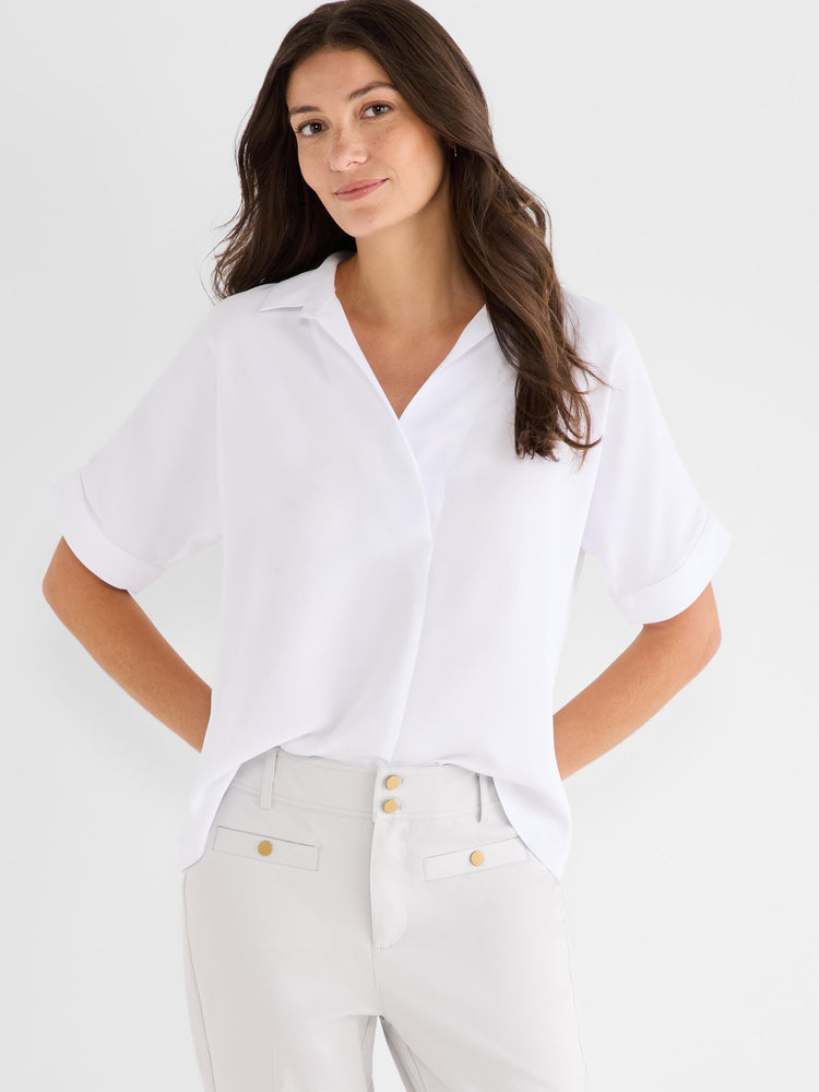 White relaxed-fit short-sleeve collared blouse worn by a model, featuring a deep V-neck and cuffed sleeves.