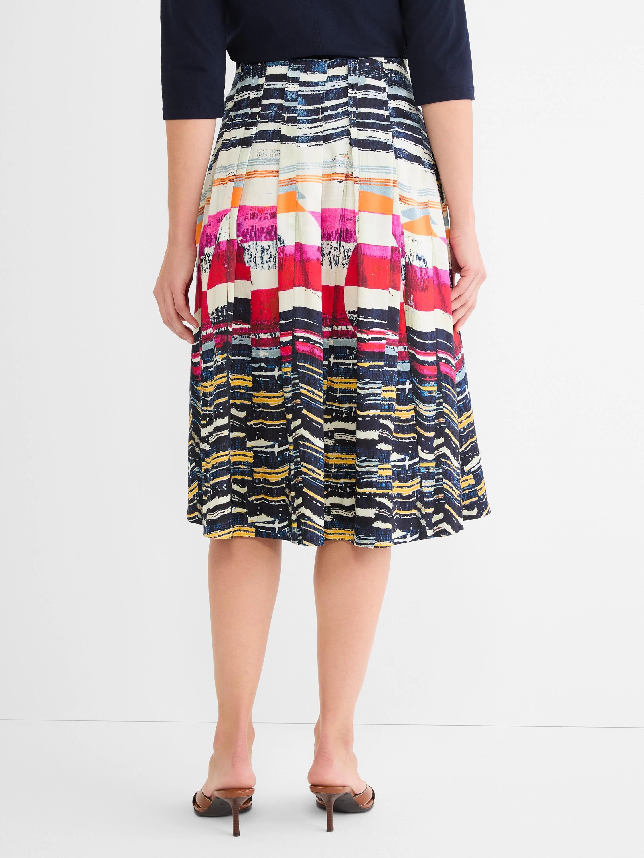 Pleated midi skirt with an abstract multi-color pattern of pink, red, orange, blue, yellow, and white blocks.