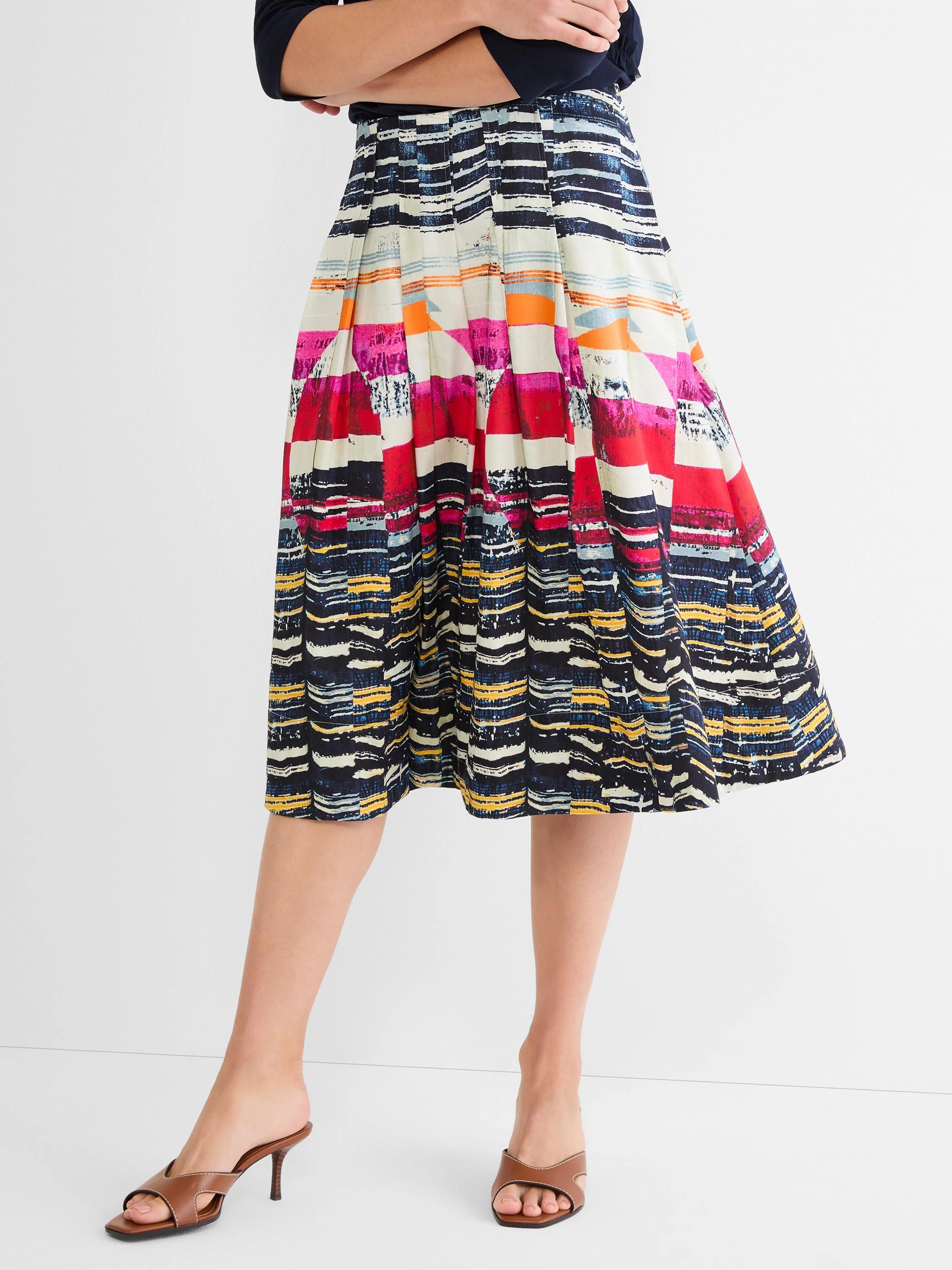 Pleated A-line midi skirt with abstract horizontal stripes in navy, white, red, pink, orange, and yellow.