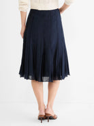 Navy A-line midi skirt with vertical stitched panels and a subtle sheer hem, shown from behind.