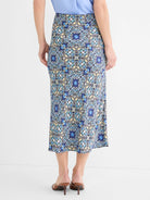 Midi slip skirt with a filigree tile pattern in blue, yellow, and white on a dark background, flowing.