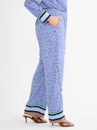 Blue mosaic wide-leg pants with light green, yellow, black, light blue, and beige striped trim on the hem.
