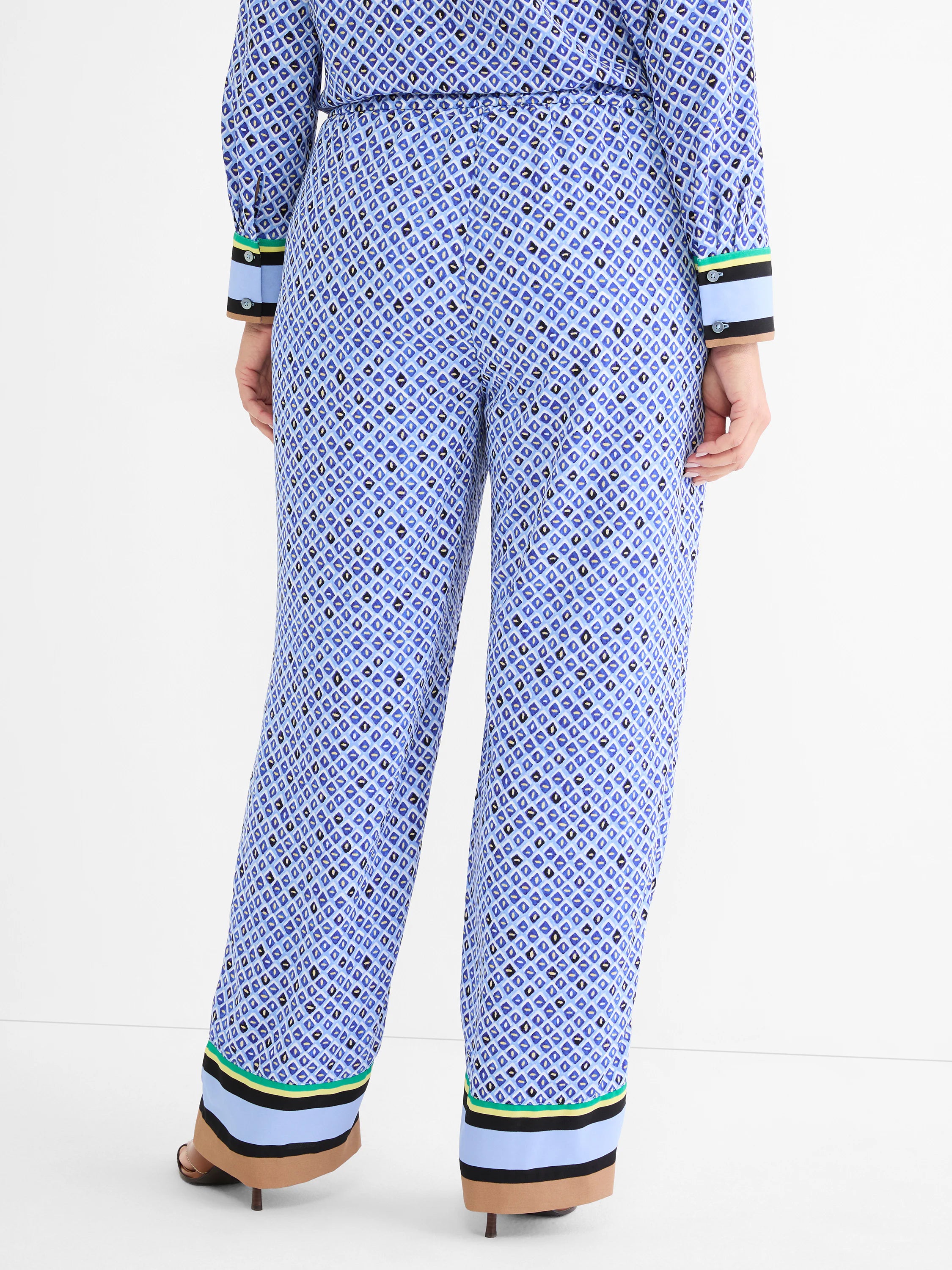 Blue mosaic wide-leg pants with green, yellow, black, light blue, and tan striped trim on hems.