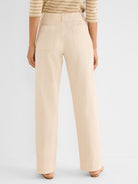 Light beige high-waisted wide-leg pants are shown from the back, detailed with large patch pockets.