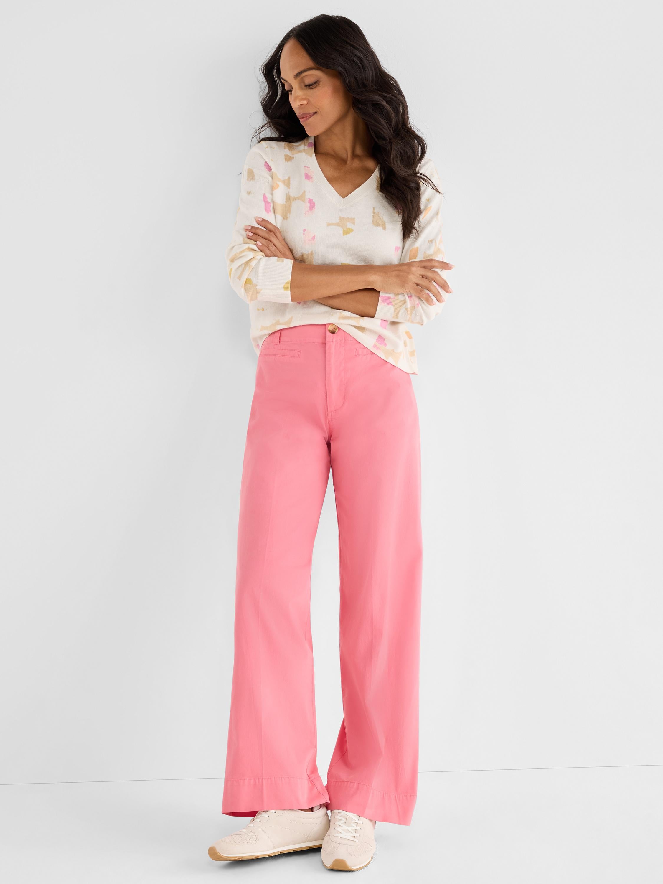 Abstract print V-neck sweater paired with fitted pink high-rise wide-leg pants for a bold casual outfit.