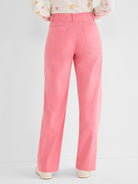 Pink high-waisted wide-leg trousers with utility styling are shown from the back, featuring large patch pockets.