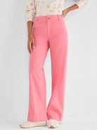 Bright pink high-waisted pants with a wide, straight leg and a flat front closure are styled on the model.