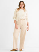 Relaxed cream wave-knit sweater and high-waisted wide-leg beige pants create a monochromatic, easy-fitting look.