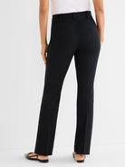 Model wears high-waisted black tailored pants with a straight fit and subtle back pockets.