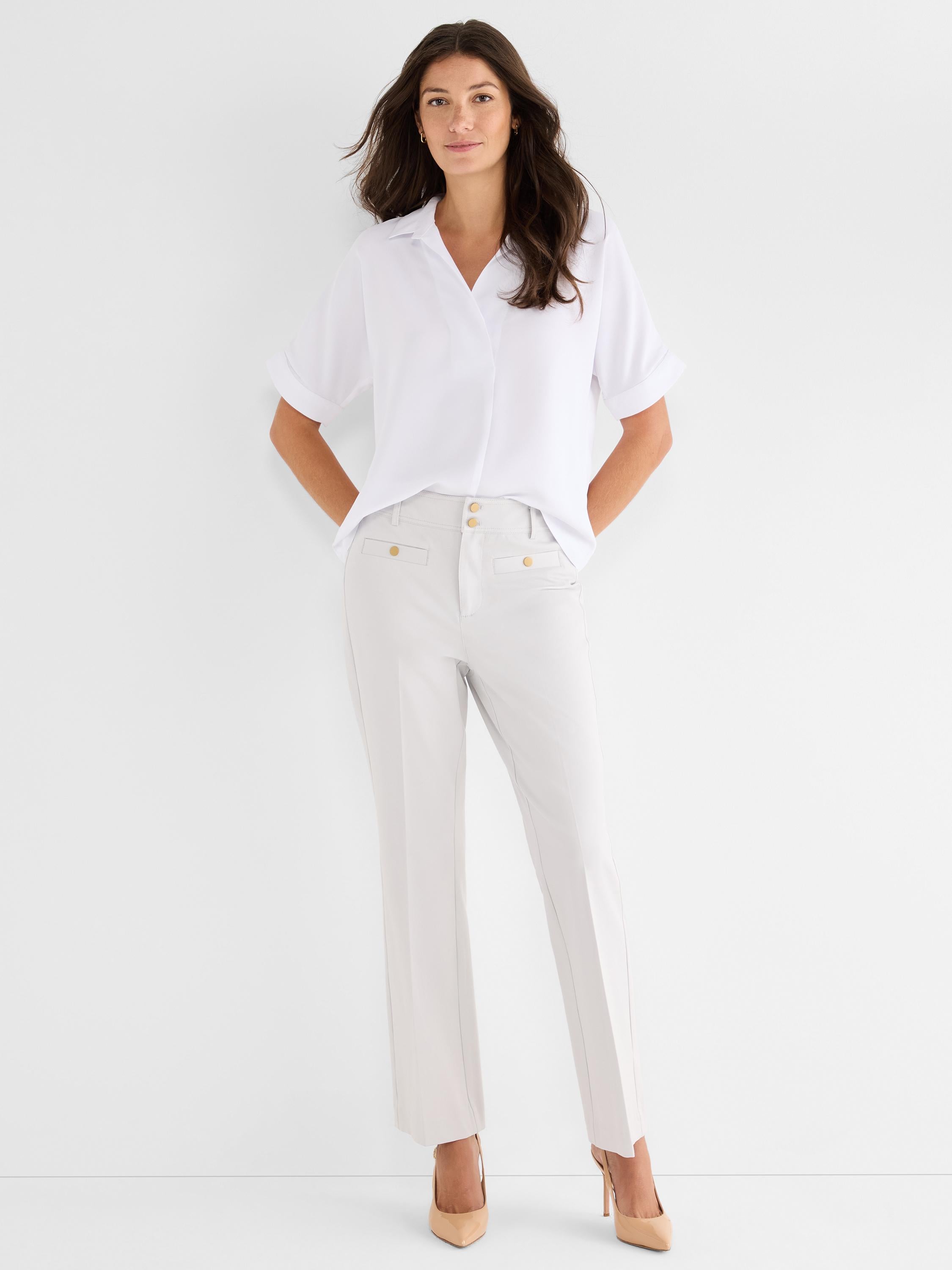 A loose white collared short-sleeve shirt is paired with high-waisted tailored light gray ankle pants accented with gold.