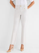 Light beige straight trousers are worn, detailed with a high waist, center creases, and four gold decorative buttons.
