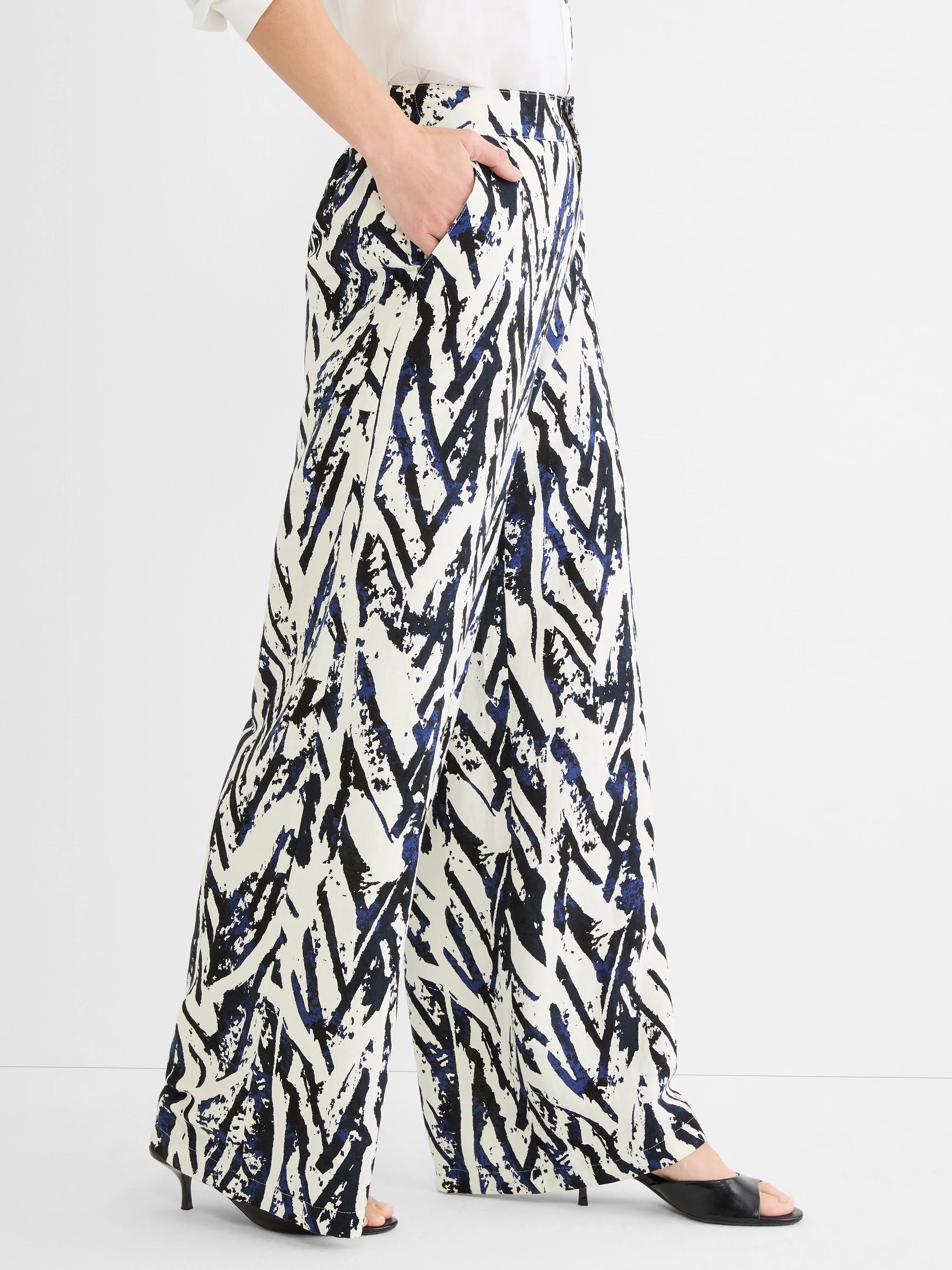 Cream linen wide-leg pants with black and indigo abstract crosshatch pattern. Model's hand in pocket.