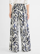 White wide-leg pants with abstract black and indigo crosshatch pattern. Gathered waist.