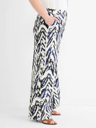 Wide-leg pants with a cream base and abstract indigo blue and black brushstroke pattern. Hand in pocket.