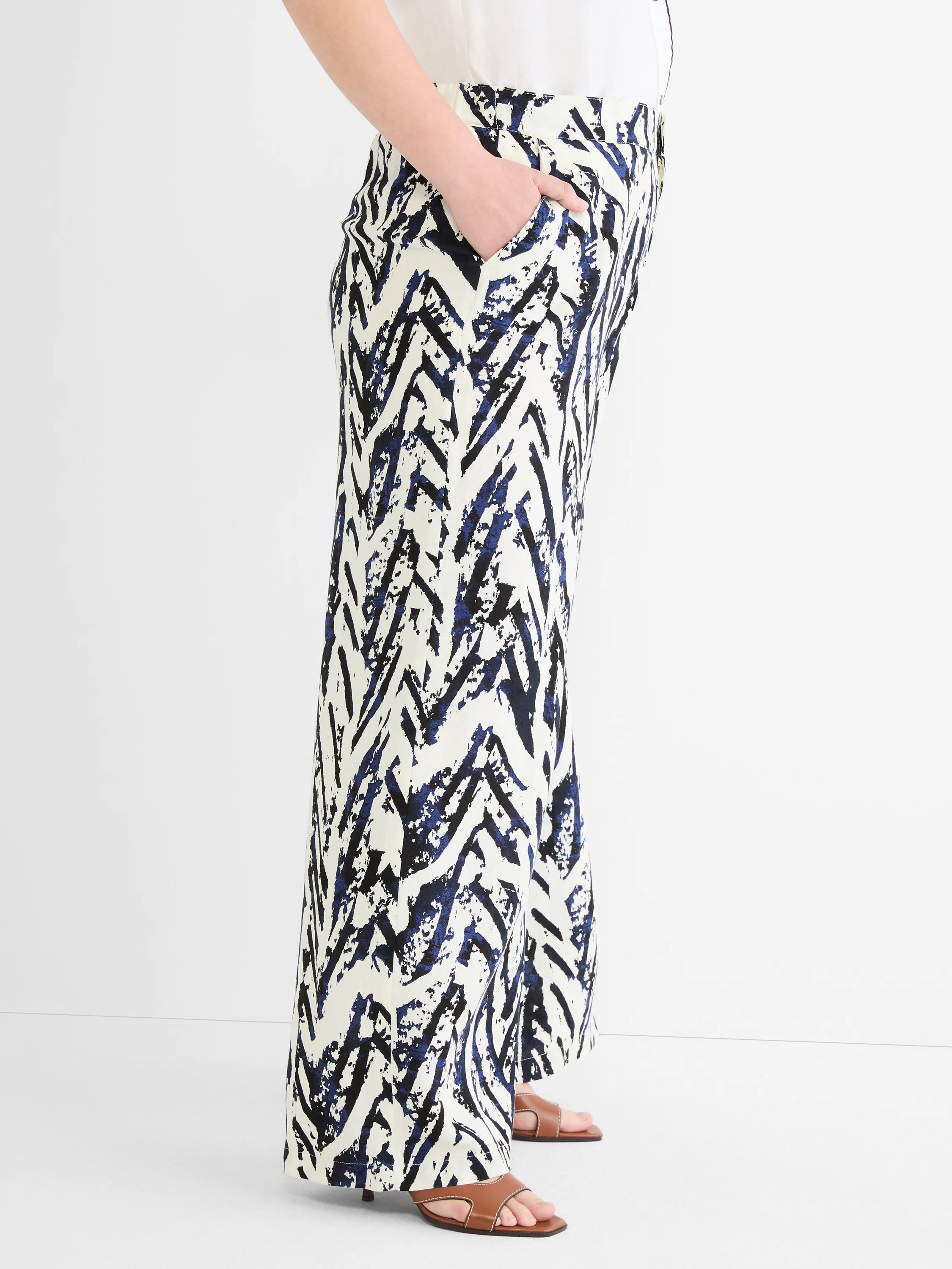 Wide-leg pants with a cream base and abstract indigo blue and black brushstroke pattern. Hand in pocket.