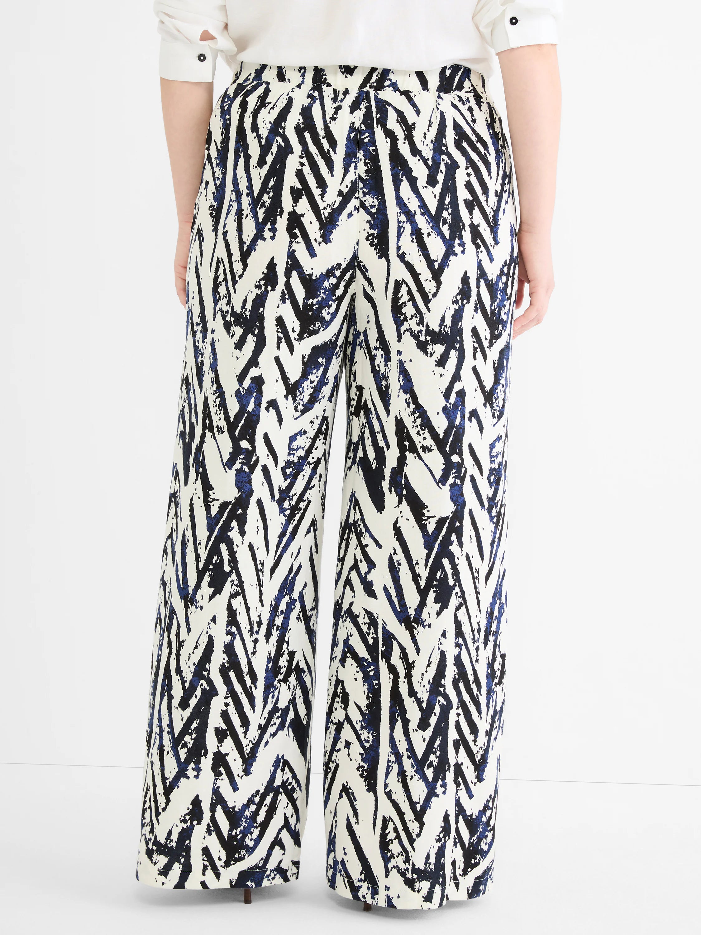 Wide-leg pants with an abstract crosshatch pattern in indigo and black on white fabric, seen from the back.