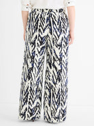 Wide-leg pants with an abstract crosshatch pattern in indigo and black on white fabric, seen from the back.