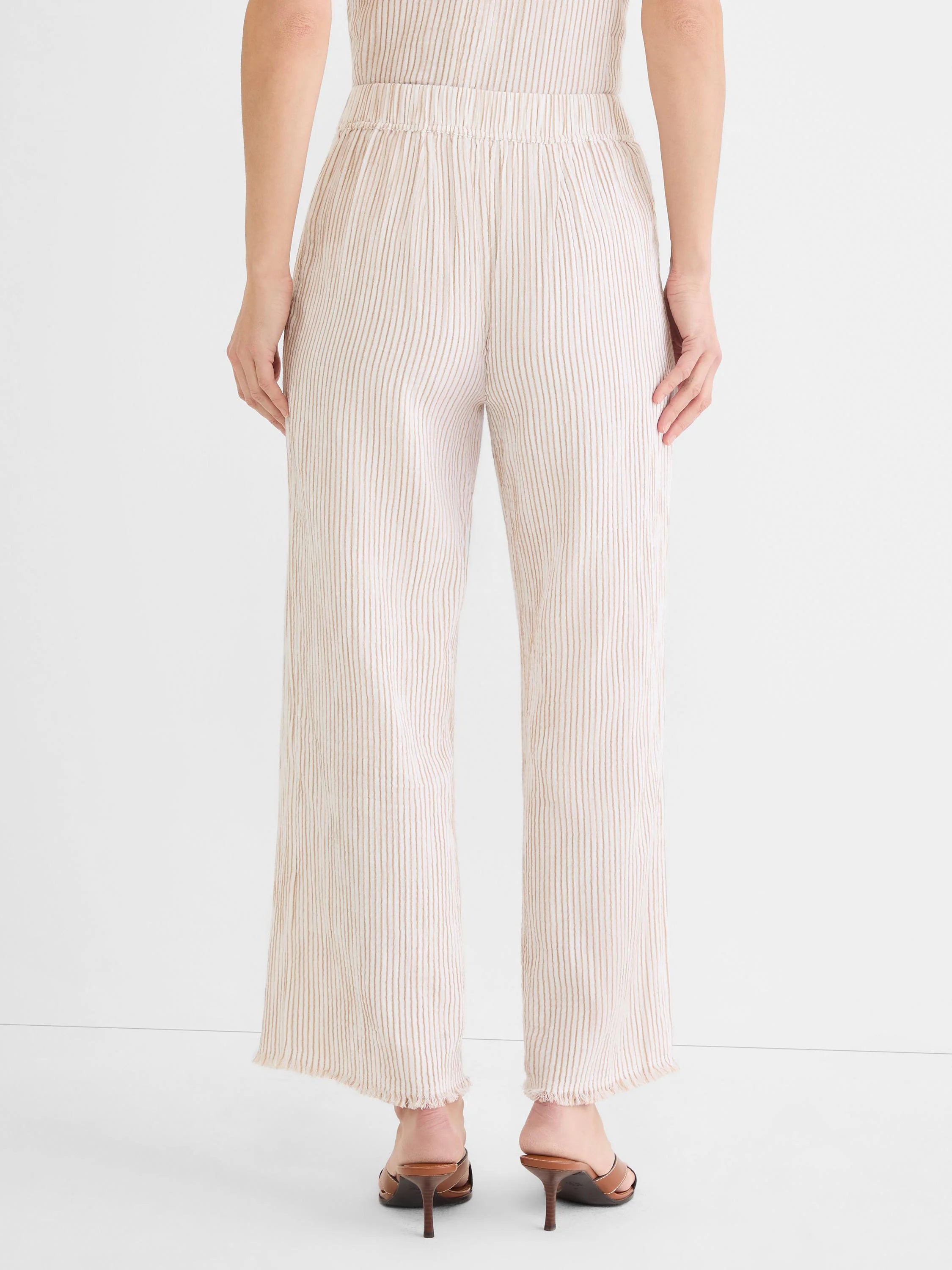 Cream wide-leg pants with vertical tan pinstripes, an elastic waist, and frayed hems.