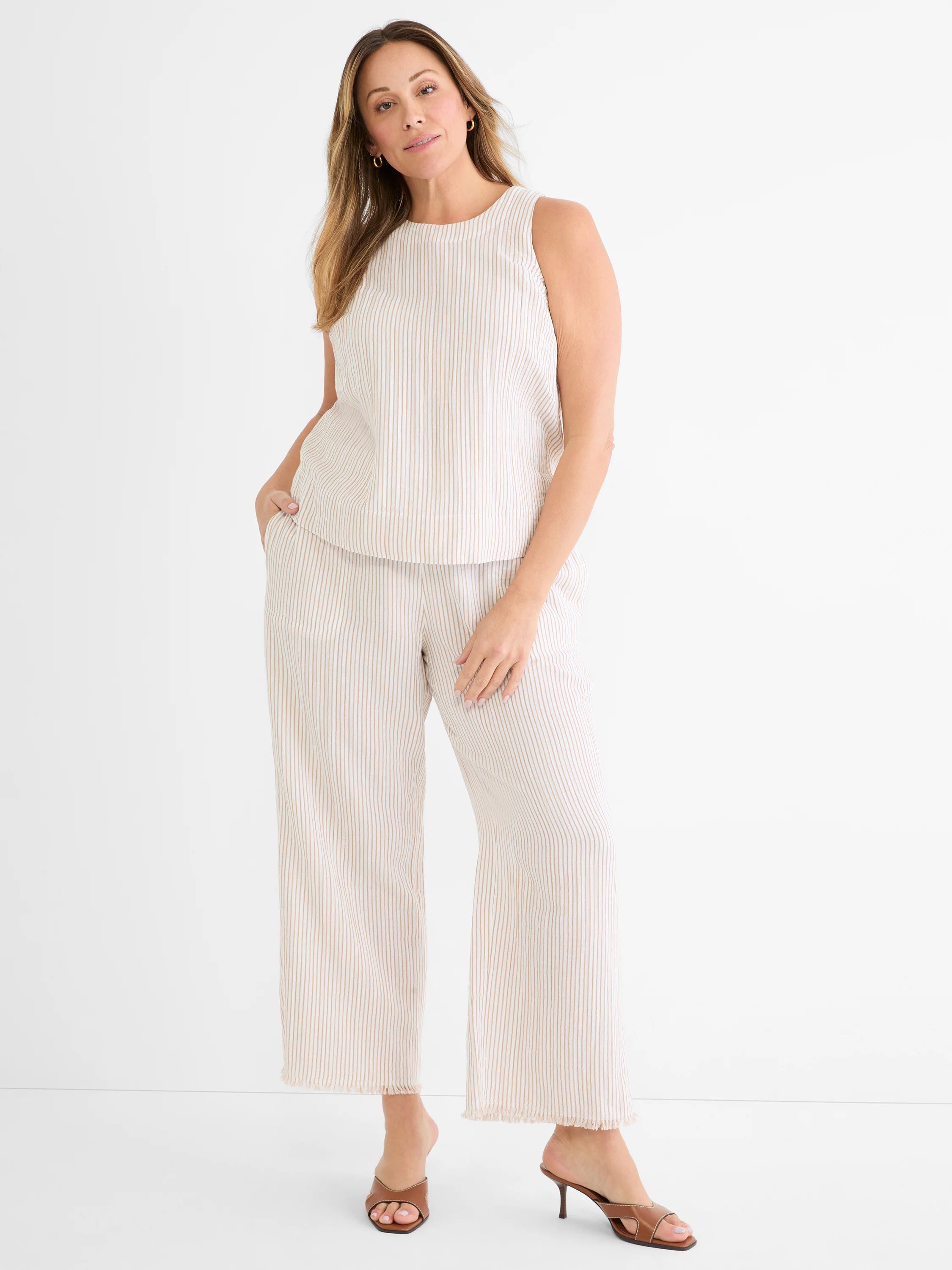 Light cream wide leg gauze pants with tan pinstripes and a frayed hem.