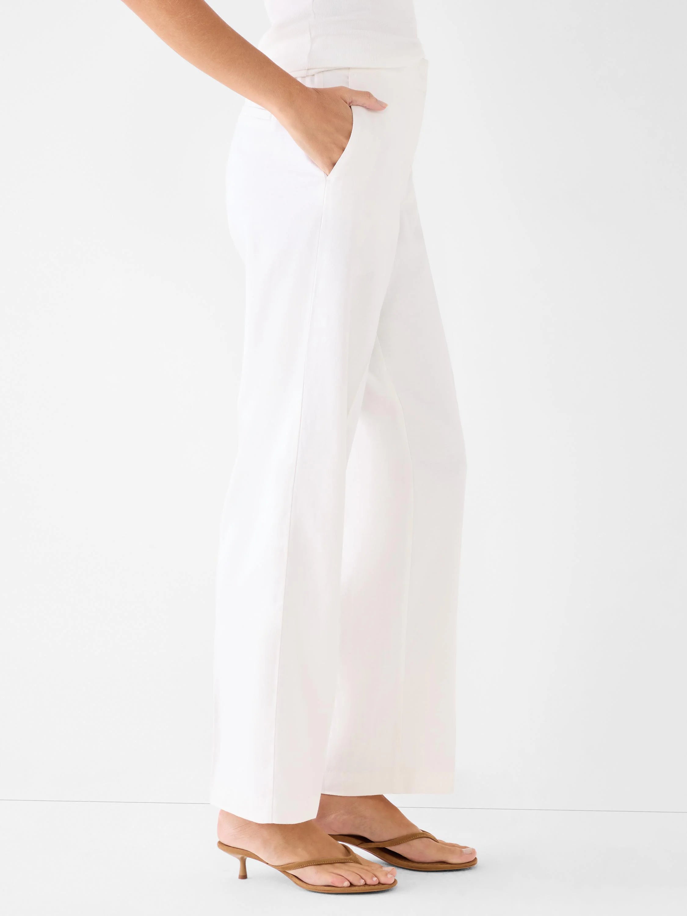 White wide-leg linen pants, full-length, with a hand in the pocket.