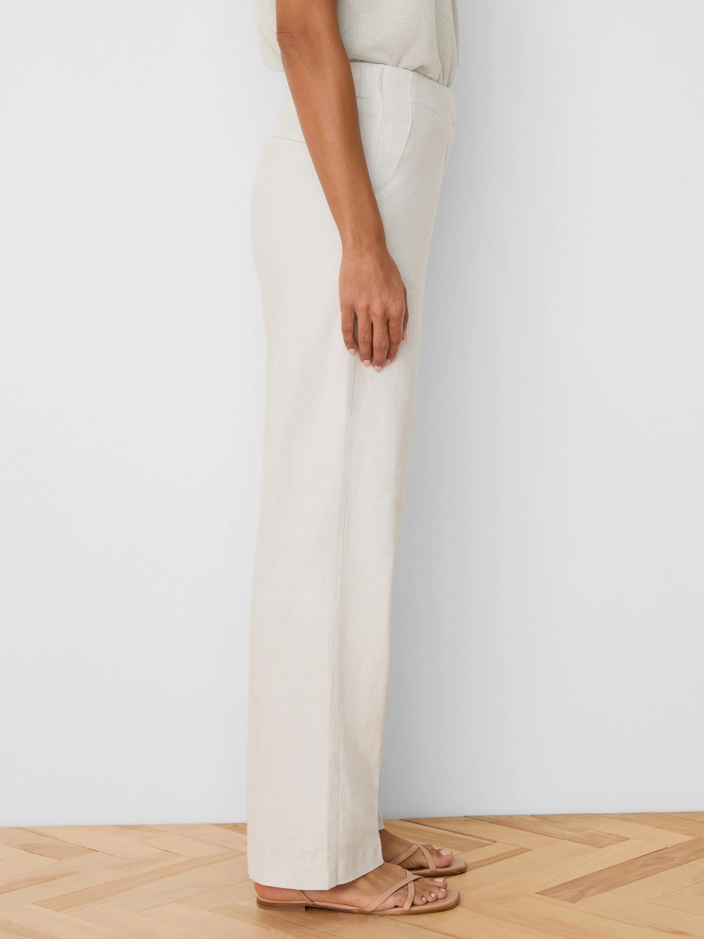 Light beige wide-leg linen pants, side view. Features visible linen texture, side pockets, and a relaxed drape.