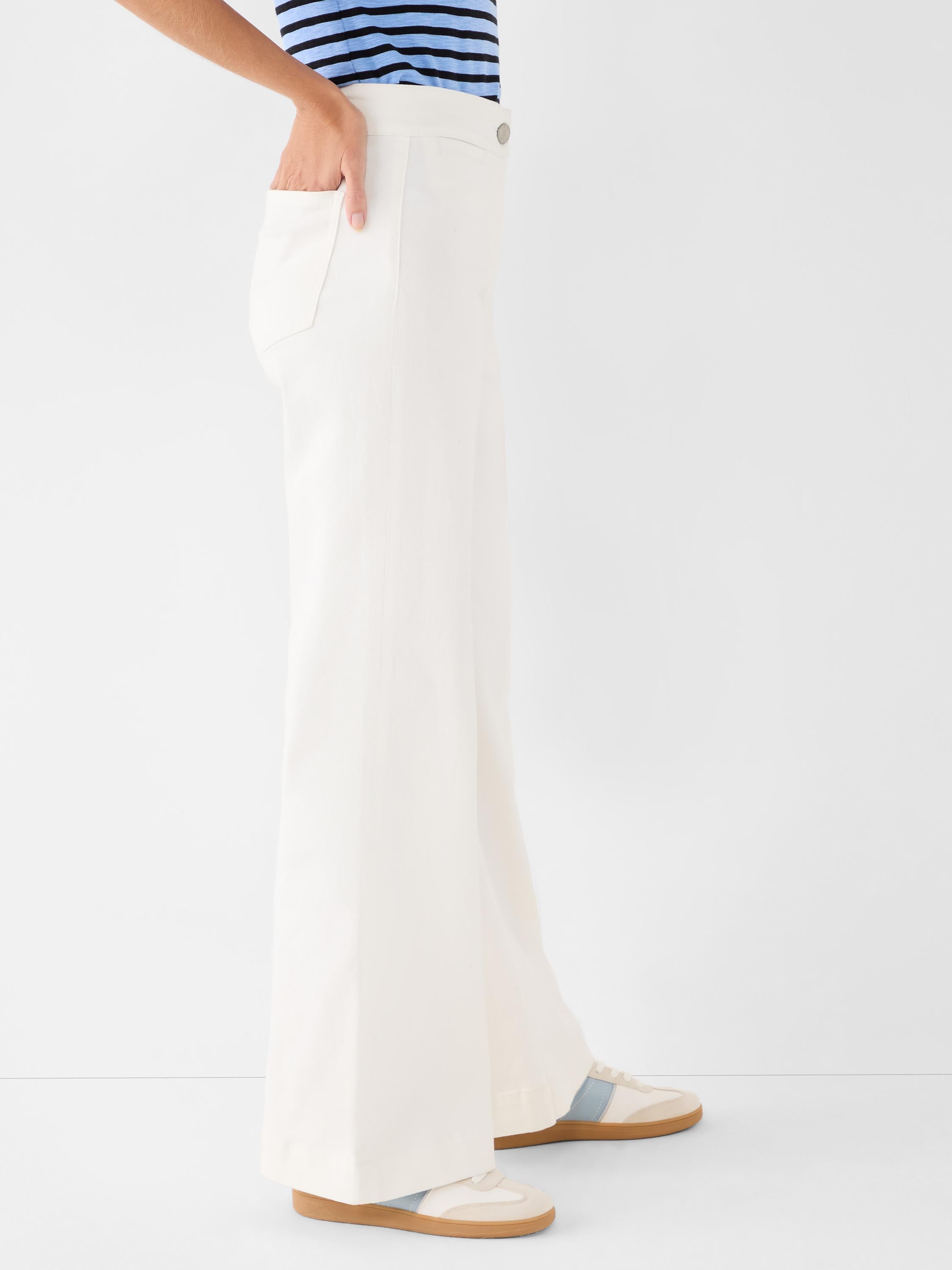 Cream high-waisted wide-leg trousers are shown on a model with a clean flat front and relaxed fit.