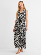 Black and white cursive pattern sleeveless maxi dress with a V-neck and drawstring waist on a model.