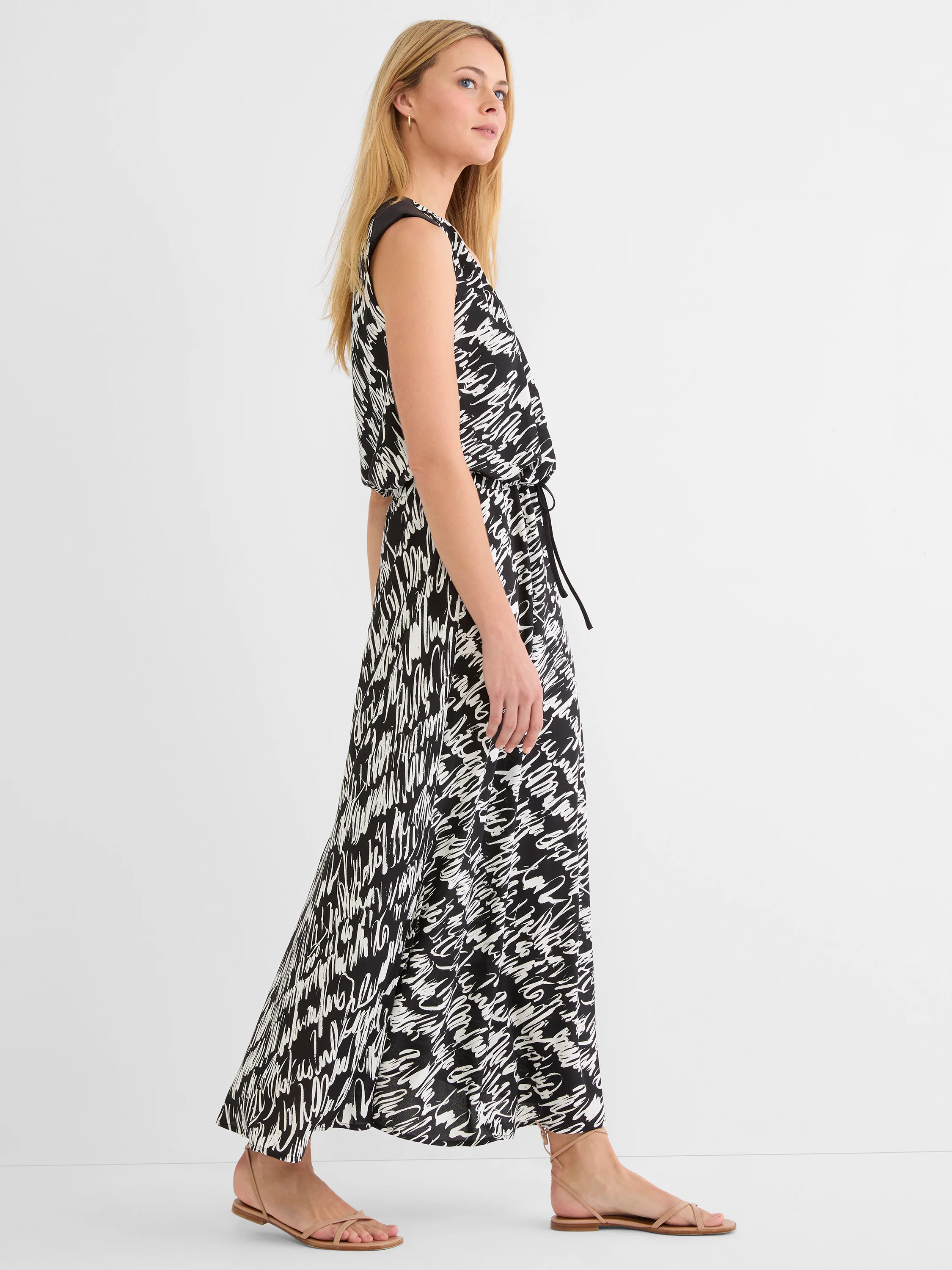 Sleeveless black and white maxi dress with an abstract white cursive script pattern and a tie-waist.