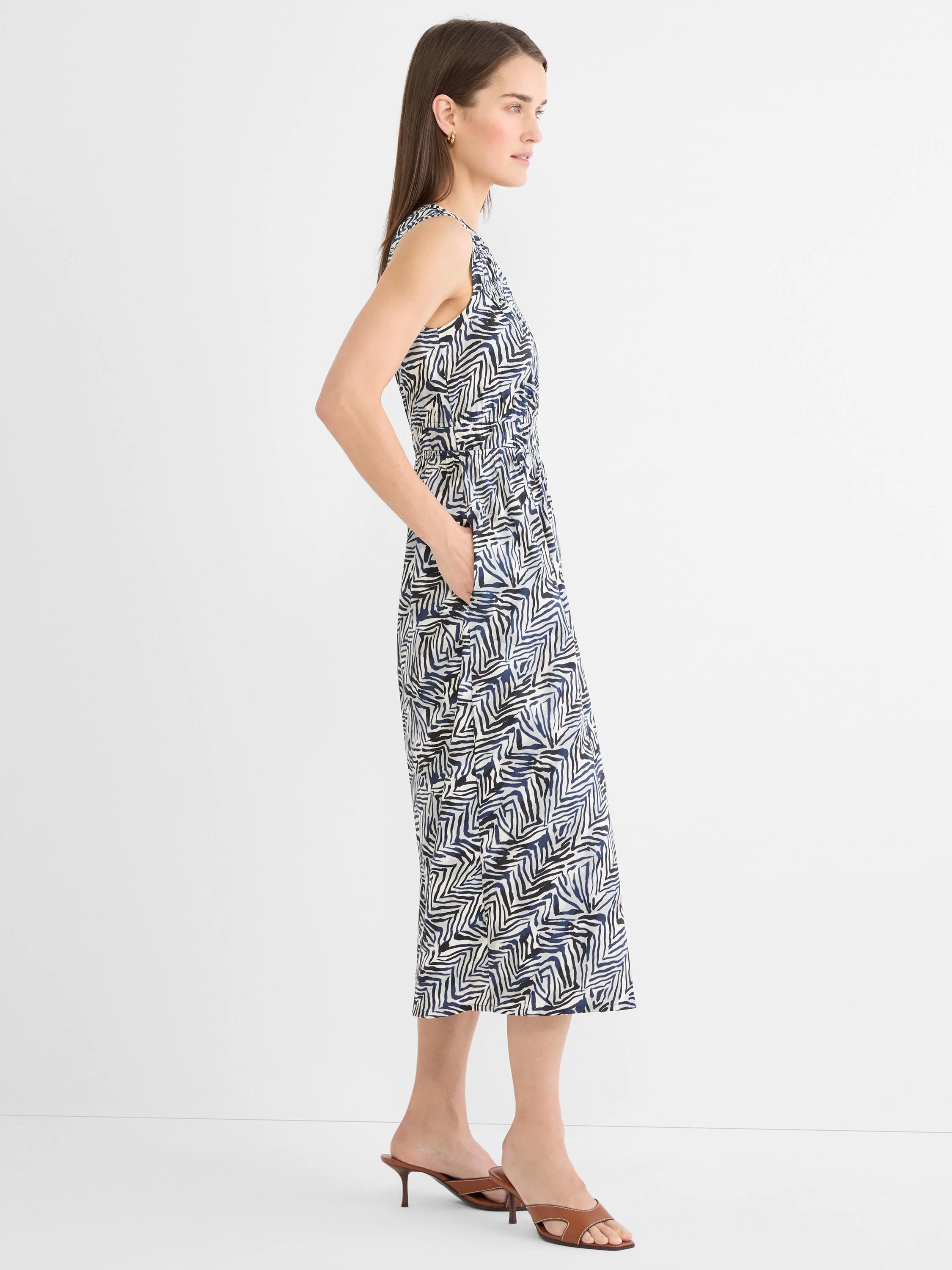 Sleeveless V-neck midi dress with elastic cinched waist and pockets. Features a cream, black, and navy abstract zig-zag...