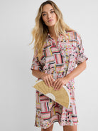 This relaxed shirt dress features a vibrant multi-colored geometric pattern, short sleeves, and a classic collar.