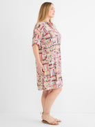 A relaxed multicolor geometric print shirt dress features a collar, cuffed short sleeves, and hits above the knee.